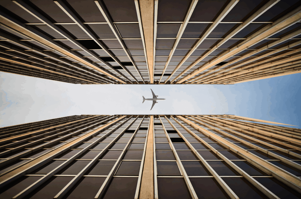 Airplane flying between high-rise buildings symbolizing proximity to airport in SeaTac commercial ground lease property