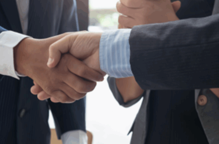 Close-up of business handshake in suits representing trusted advisor partnership and family office real estate collaboration