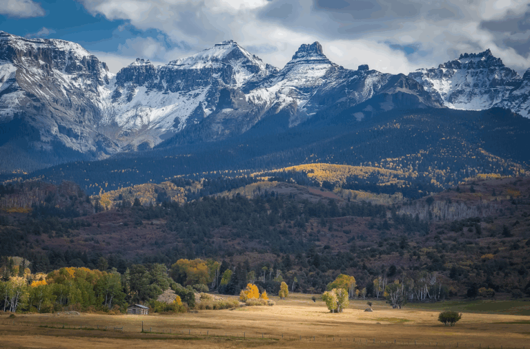 Expansive legacy land investment at the base of snow-capped mountains with autumn colors, symbolizing long-term family office stewardship