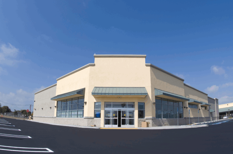 Exterior of stabilized retail strip center with ample parking and modern facade, part of income-producing real estate for family office portfolio